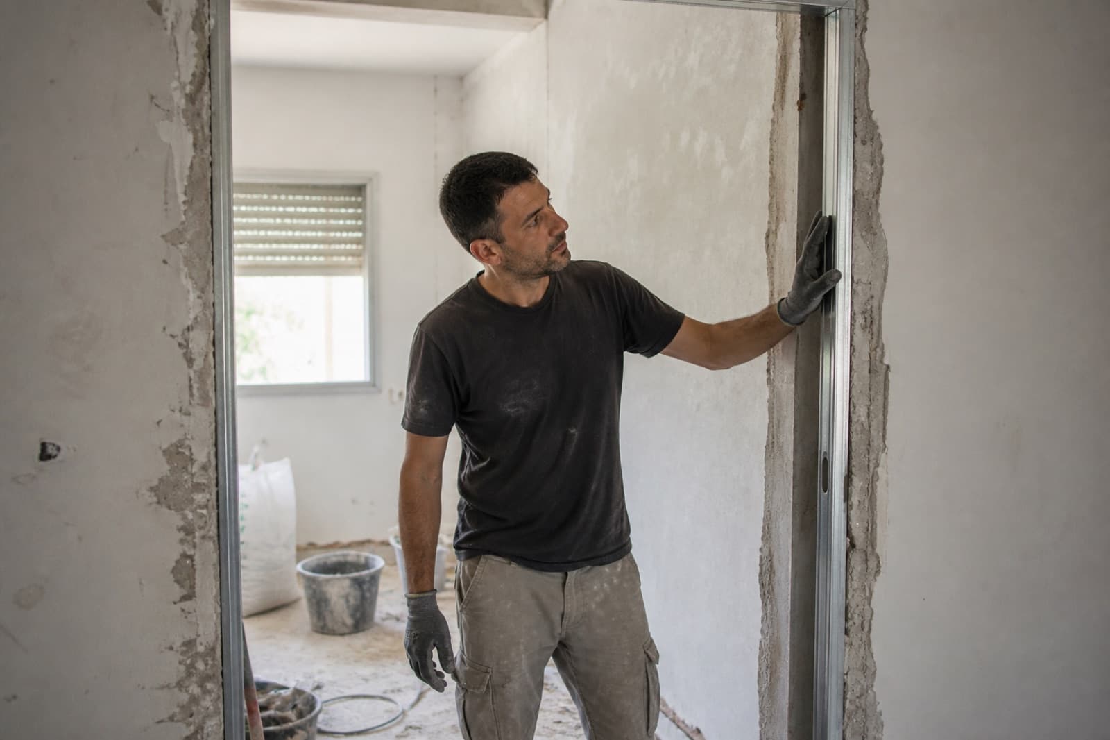 שיפוצניק בדירה ישראלית באמצע שיפוץ, כלי עבודה וקירות חשופים באור יום